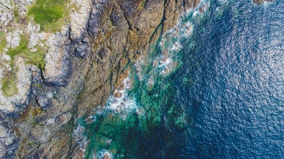 航空摄影的岩石海岸附近的青草覆盖的山
